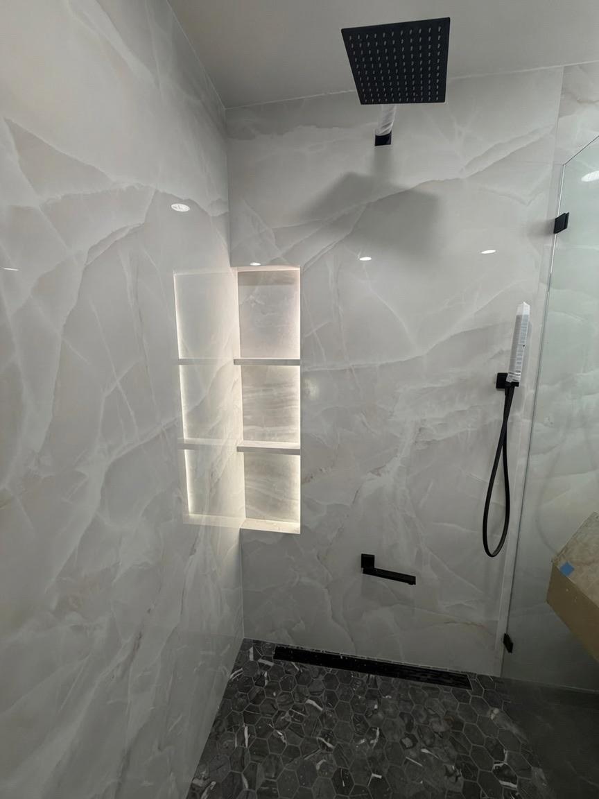 Onyx shower with a backlit niche and recessed lighting.