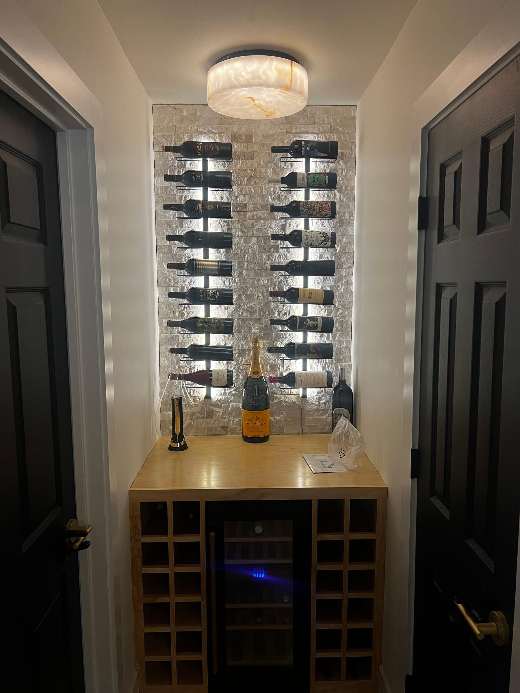 Backlit stone wine wall with illuminated display racks and an onyx ceiling light.